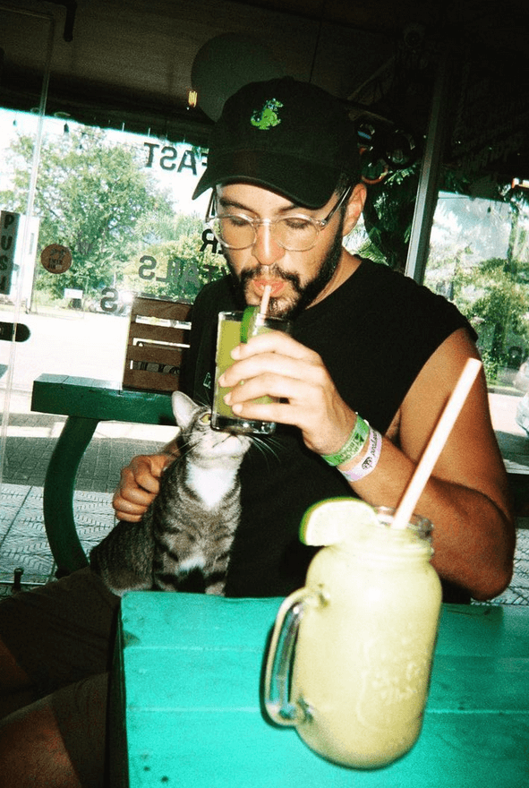 A portrait of Luke drinking a smoothie with a cat.